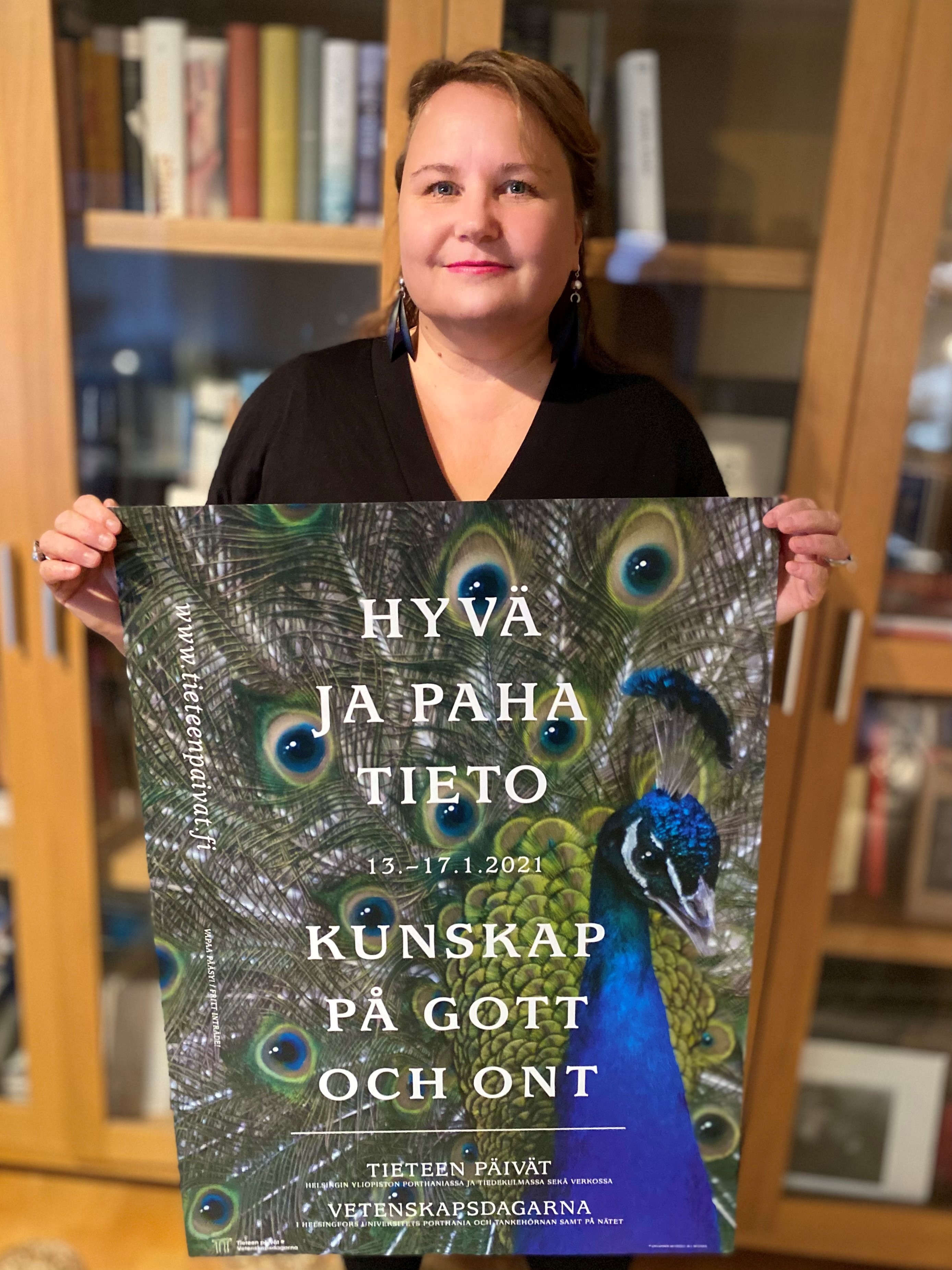 Graafinen muotoilija Marja-Leena Muukka pitelee Tieteen päivien 2021 julistetta käsissään.