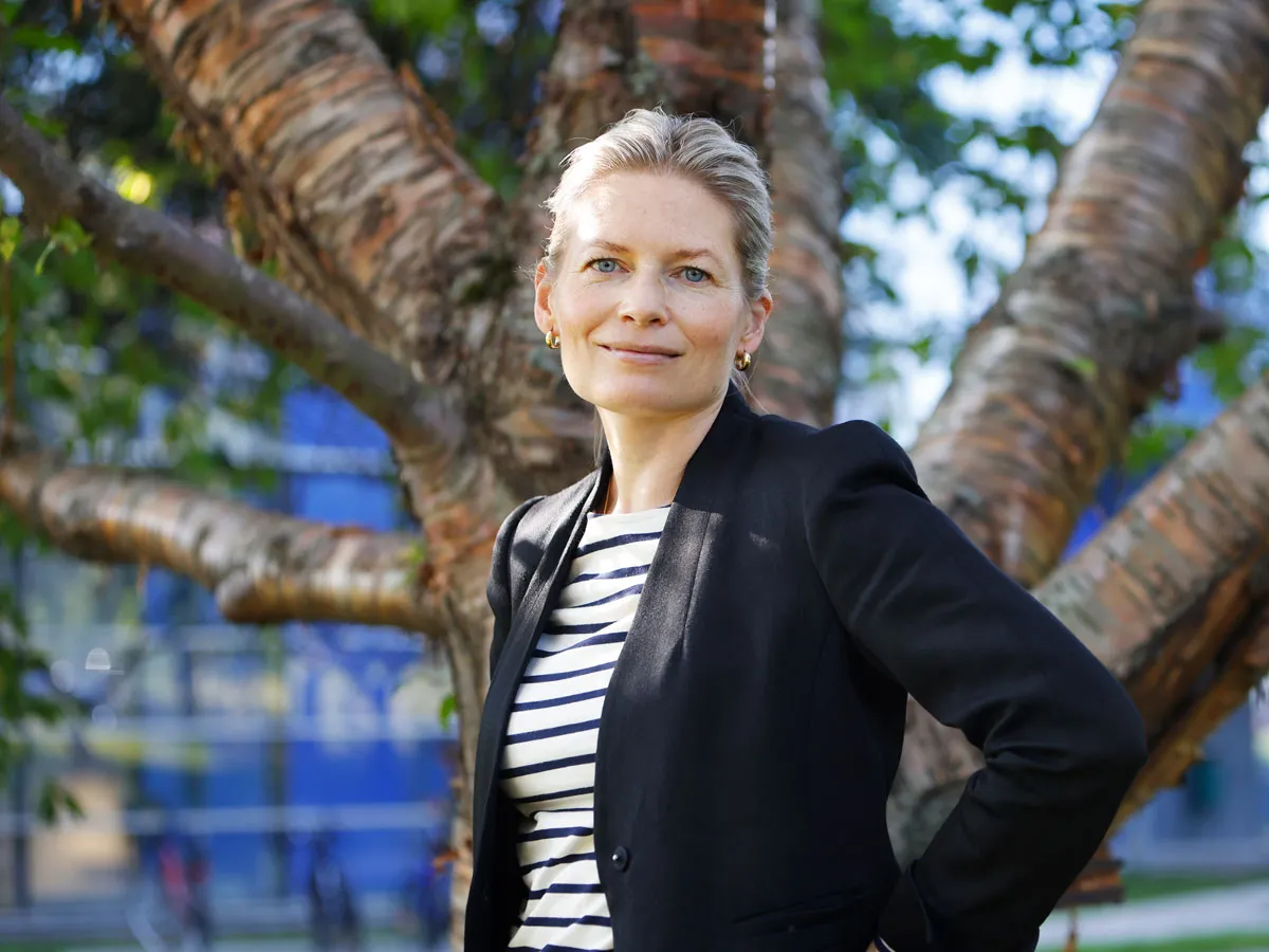 Anna-Liisa Laine katsoo kameraan. Taustalla näkyy puu.