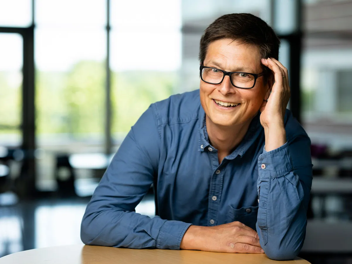Tomas Roslin nojaa pöytään ja katsoo kameraan.